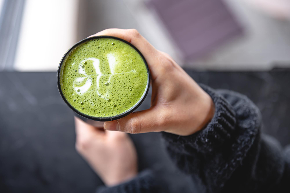 Tasse de thé vert matcha en vue de dessus de main de femme